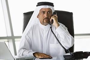 Businessman in office on telephone by laptop (high key/selective focus)