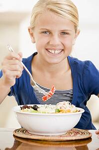 Young girl indoors eating seafood smiling
