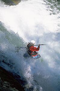 Kayaker in rapids going over waterfall