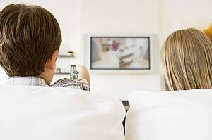 Young boy and young girl in living room with remote control and flat screen television