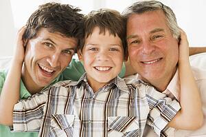 Grandfather with son and grandson smiling.
