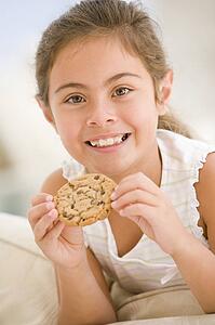 Young girl eating cookie in living room smiling