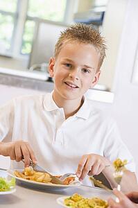 Student in cafeteria eating lunch (selective focus)