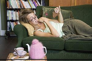 Young woman lying on sofa at home eating chocolate
