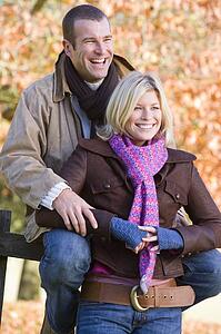 Couple outdoors in park by fence smiling (selective focus)