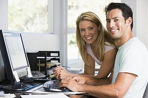 Couple in home office with computer smiling