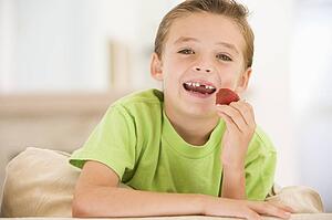 Young boy eating strawberries in living room smiling