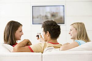 Three friends in living room watching television smiling