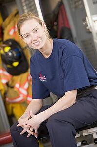 Firewoman sitting on bench in fire station locker room