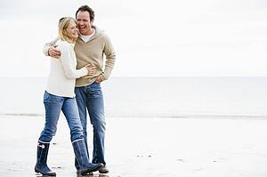 Couple walking on beach arm in arm smiling