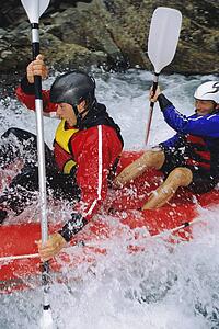 Two kayakers rowing in rapids and smiling (selective focus)