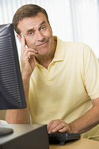 Man sitting at a computer terminal bored (high key)