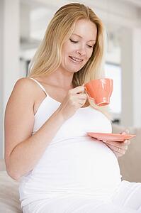 Pregnant woman with cup of tea smiling