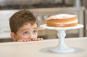Young boy in kitchen looking at cake on counter