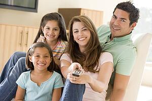 Family in living room with remote control smiling