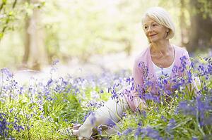 Woman sitting outdoors with flowers smiling