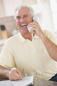 Man in kitchen on telephone laughing