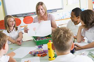 Students in art class with teacher showing a drawing
