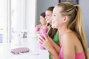 Three young women having a cold drink in a cafeteria