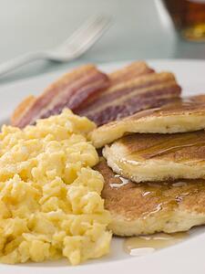 American Pancakes with Crispy Bacon and Scrambled Eggs and Maple Syrup