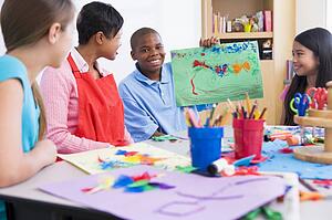 Student showing teacher and classmates his artwork (selective focus)
