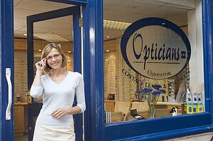 Woman standing at front entrance of optometrists smiling