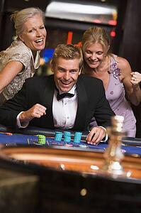 Three people in casino playing roulette smiling (selective focus)