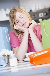 Exhausted young woman sitting at a table taking a break from shopping