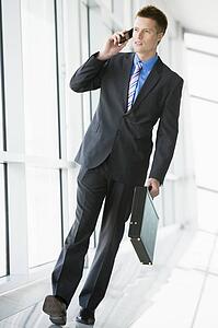 Businessman walking in corridor using cellular phone