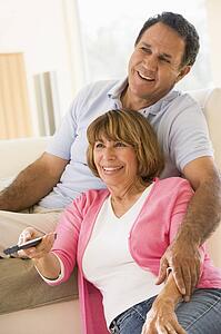 Couple in living room with remote control smiling