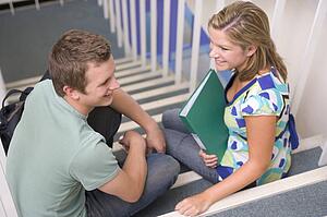 Two students sitting on staircase with notebooks (selective focus)