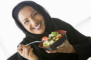 Woman eating salad and smiling (high key/selective focus)