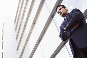 Businessman standing outdoors by building (high key/selective focus)