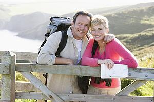 Couple on cliffside outdoors leaning on railing and smiling