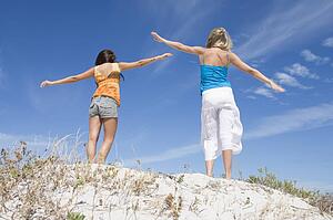Two young women posing on a sand hill