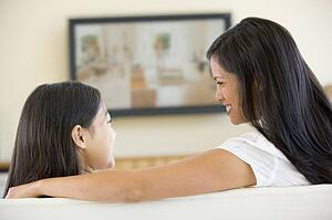 Woman and young girl in living room with flat screen television smiling