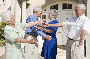 Two senior couples greeting each other with open arms