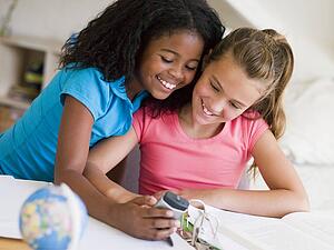 Young Girls Distracted From Their Homework, Playing With A Cellphone