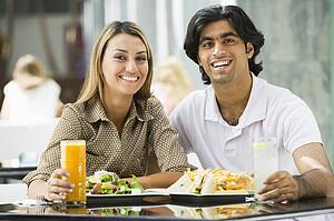 Couple at restaurant eating and smiling (selective focus)