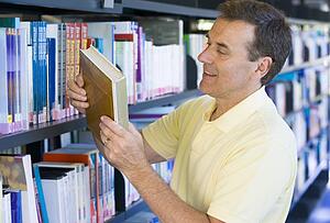 Man in library looking at book (depth of field)
