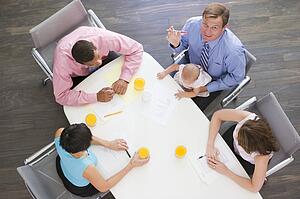 Four businesspeople in boardroom with one holding a baby