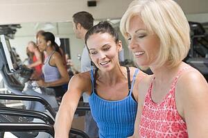 Personal Trainer Showing Woman How To Use Treadmill