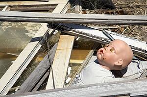 Old baby doll head sticking out of garbage at landfill