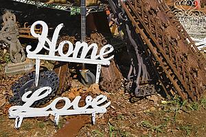 Metal garden decorations of words Love and Home next to rusted metal objects