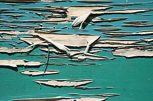 Side of wall with green peeling paint.