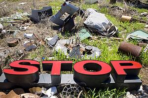 Word 'STOP' lying amongst junk and garbage.