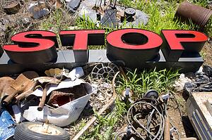 Word 'STOP' lying amongst junk and garbage.