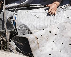 Old baby doll hand sticking out of garbage at landfill.