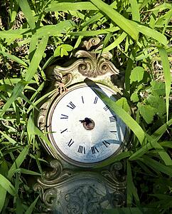 Broken clock lying in grass.