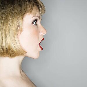 Profile portrait of young blonde woman who's mouth is open in shock.